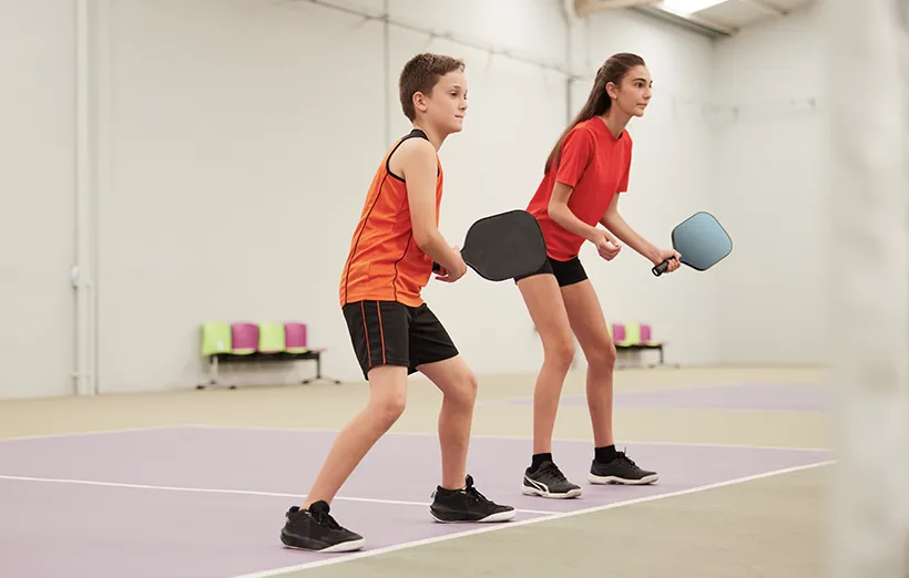 Young teenager boy and girl playing pickleball.