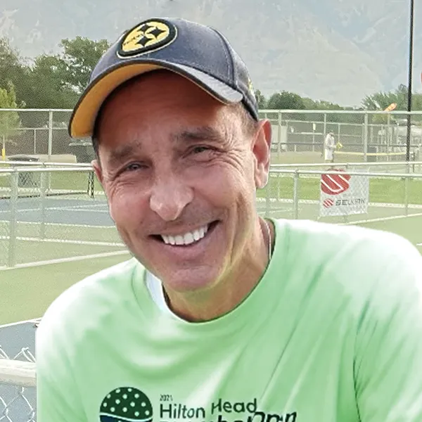 Portrait of Justin Umbs with pickleball court and hills in the background