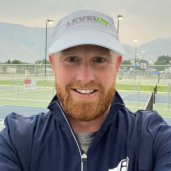 Portrait of Justin Umbs with pickleball court and hills in the background