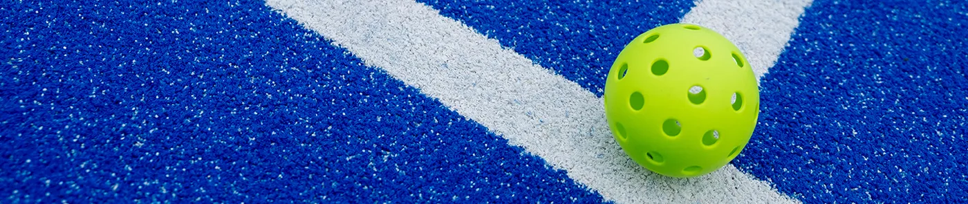 green pickleball on blue and white court surface