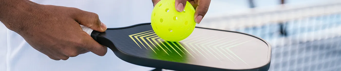 close-up of hands holding pickleball and paddle