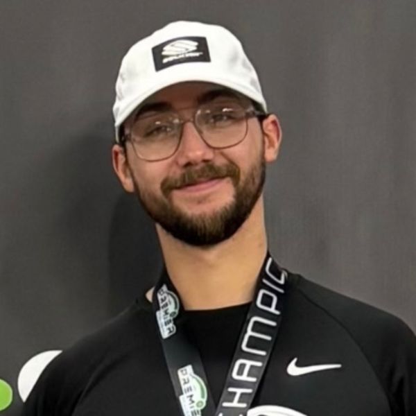 Portrait of Joe Campana smiling and wearing a hat